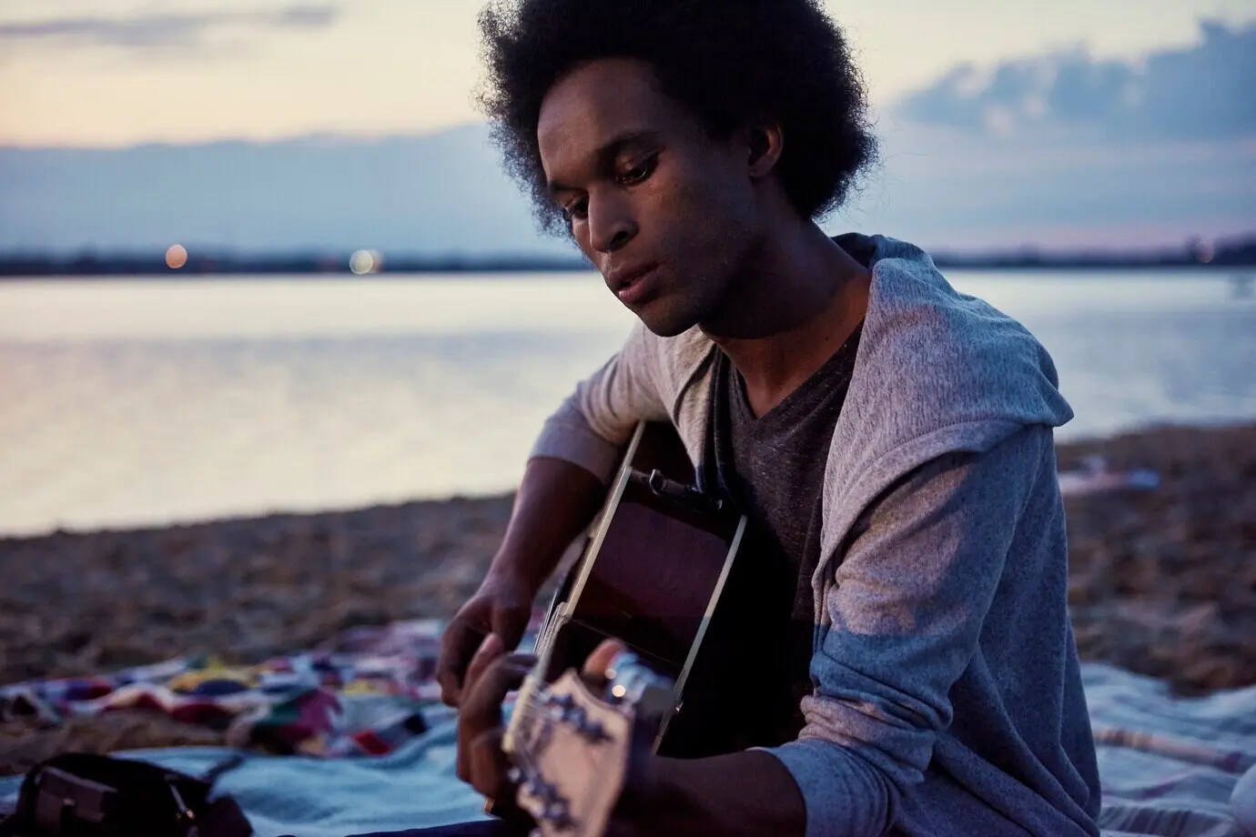 Ein afrikanischer Mann spielt nachts am Strand Gitarre.